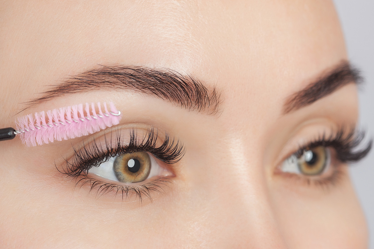 Beautiful young girl with long eyelashes tweezing her eyebrows in a beauty salon. Woman doing eyebrow permanent makeup correction. Microblading brow.